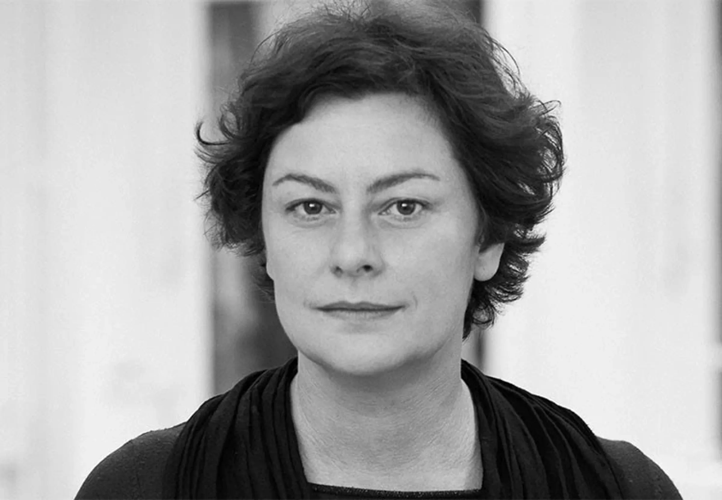 Black-and-white portrait of a person with short, curly hair and a neutral facial expression.