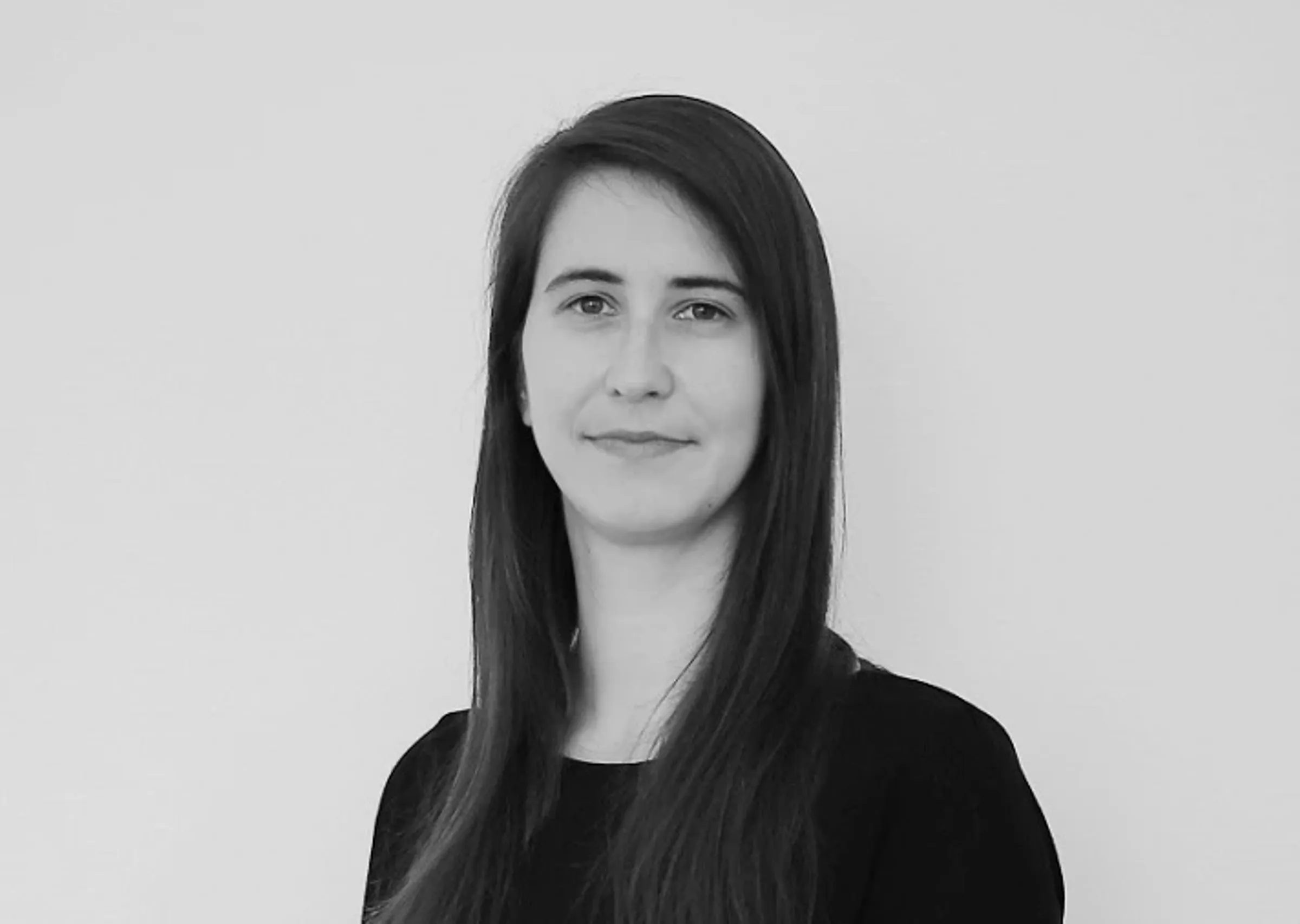 Portrait of a woman with long hair in front of a neutral background.