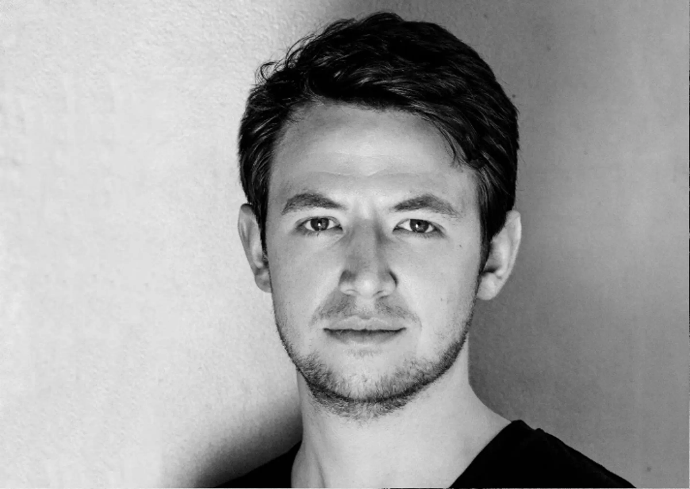 Black-and-white portrait of a man with short hair and a neutral facial expression.
